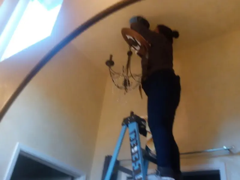 Electrician installing a chandelier in a Lee Acres residence